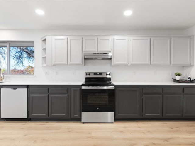 kitchen with backsplash, white cabinetry, stainless steel appliances, and light wood-type flooring