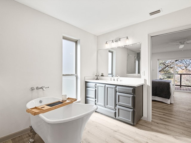 bathroom with hardwood / wood-style floors, vanity, ceiling fan, and a washtub