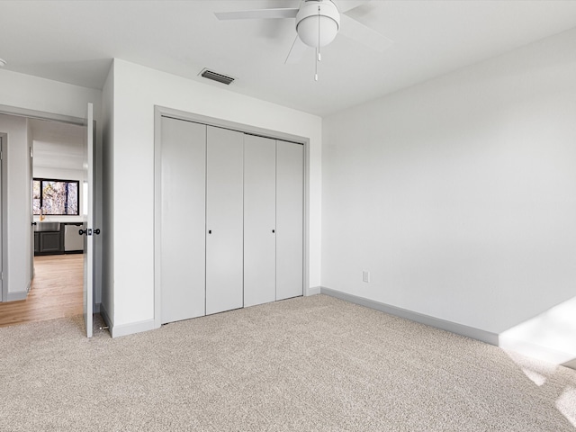 unfurnished bedroom featuring ceiling fan, light colored carpet, and a closet