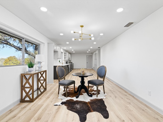 dining area with light hardwood / wood-style floors and an inviting chandelier