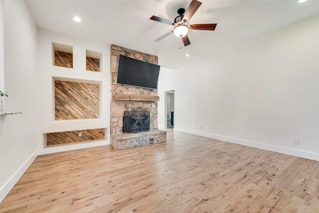 unfurnished living room featuring a stone fireplace, ceiling fan, light hardwood / wood-style flooring, and built in features