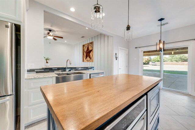 kitchen featuring white cabinets, decorative light fixtures, stainless steel appliances, and a kitchen island