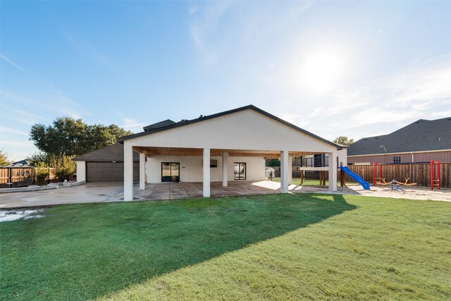 rear view of property featuring a playground, a patio area, and a yard