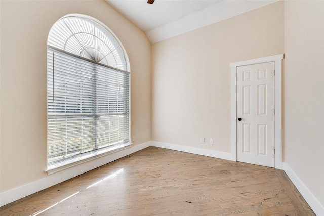 spare room with vaulted ceiling and light wood-type flooring