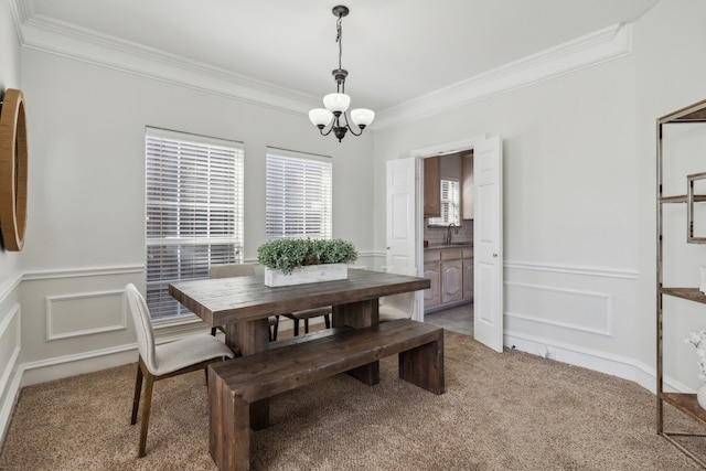 dining area with sink, light colored carpet, ornamental molding, and a notable chandelier