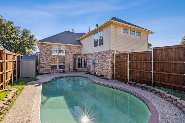 rear view of property featuring a fenced in pool and a storage shed