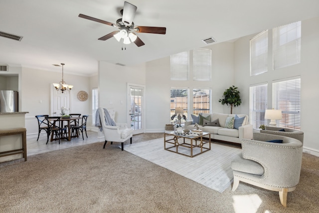 carpeted living room featuring ceiling fan with notable chandelier and ornamental molding