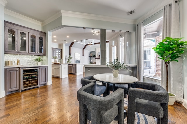 dining area with wine cooler, dark hardwood / wood-style flooring, indoor bar, and ornamental molding