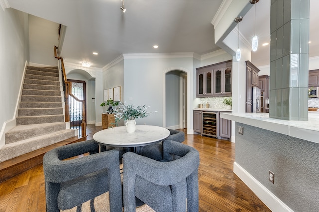 dining room with hardwood / wood-style floors, crown molding, beverage cooler, and bar area