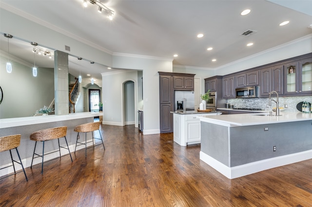 kitchen featuring appliances with stainless steel finishes, dark hardwood / wood-style flooring, ornamental molding, and sink