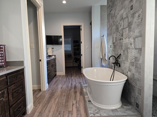 bathroom featuring a washtub, vanity, wood-type flooring, and tile walls