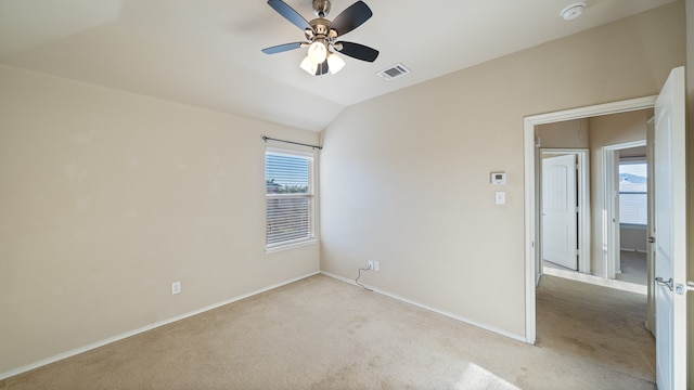 spare room featuring ceiling fan, light carpet, and vaulted ceiling