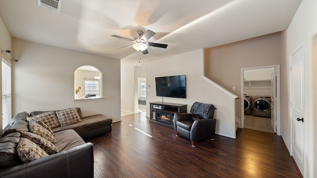 living room featuring washing machine and dryer, ceiling fan, and dark wood-type flooring