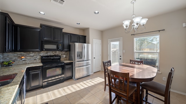 kitchen with an inviting chandelier, light stone counters, backsplash, decorative light fixtures, and black appliances