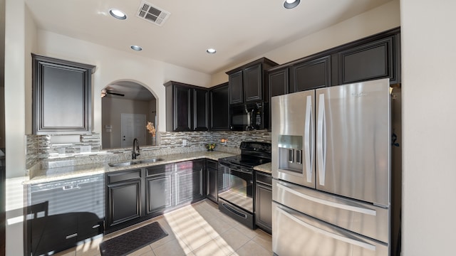 kitchen with backsplash, black appliances, sink, light stone countertops, and light tile patterned floors