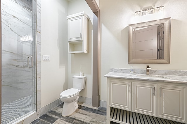 bathroom featuring a shower with door, vanity, and toilet