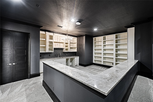 kitchen featuring pendant lighting, light colored carpet, ornamental molding, and sink