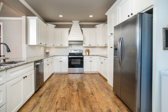 kitchen featuring white cabinetry, sink, light stone counters, custom range hood, and appliances with stainless steel finishes