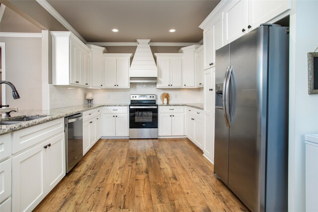 kitchen with sink, white cabinets, custom range hood, and appliances with stainless steel finishes