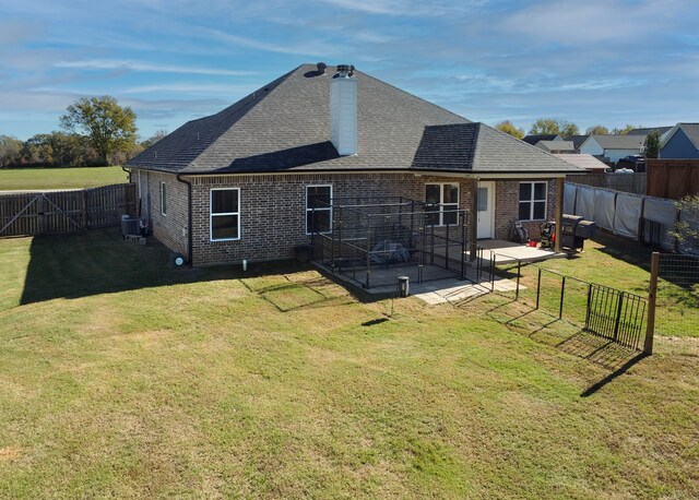 back of property with a patio, central AC, and a lawn