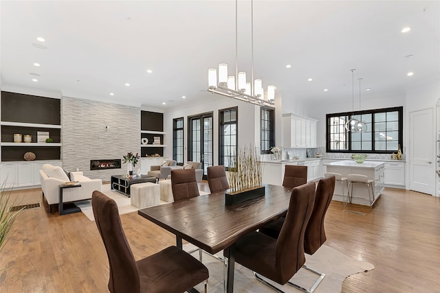 dining space with a chandelier, light wood finished floors, a fireplace, and recessed lighting