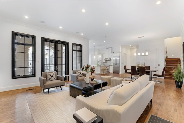 living area with recessed lighting, visible vents, stairs, ornamental molding, and light wood finished floors