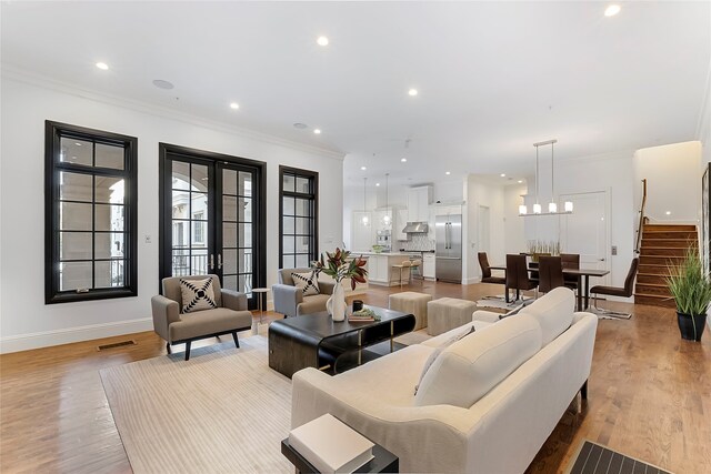 living room featuring wood-type flooring, built in shelves, crown molding, and a fireplace