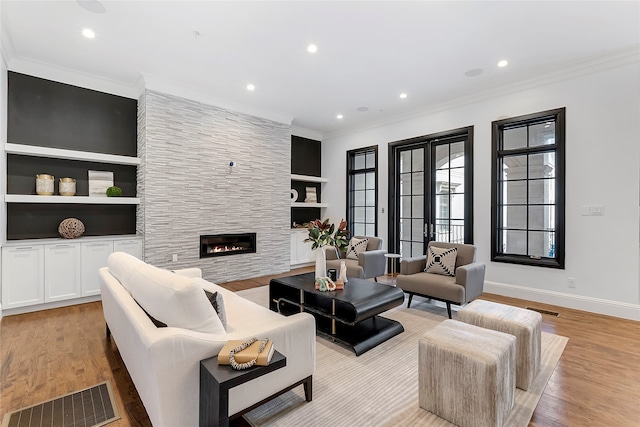 living area with ornamental molding, visible vents, a fireplace, and light wood-style flooring