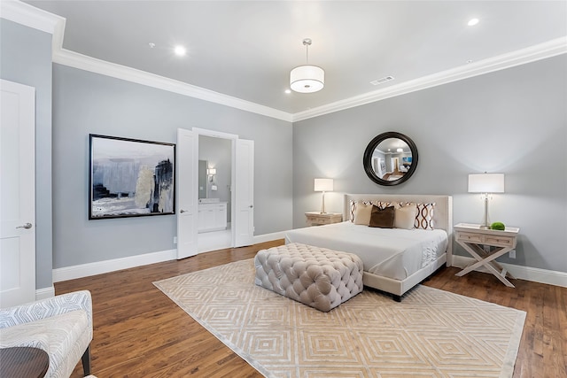 bedroom with ornamental molding, ensuite bath, wood finished floors, and baseboards