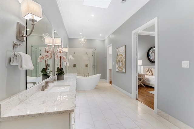 bathroom with a skylight, a freestanding bath, a shower stall, vanity, and baseboards