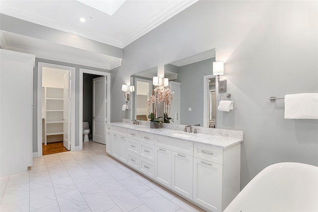 full bath with toilet, a skylight, a sink, double vanity, and crown molding