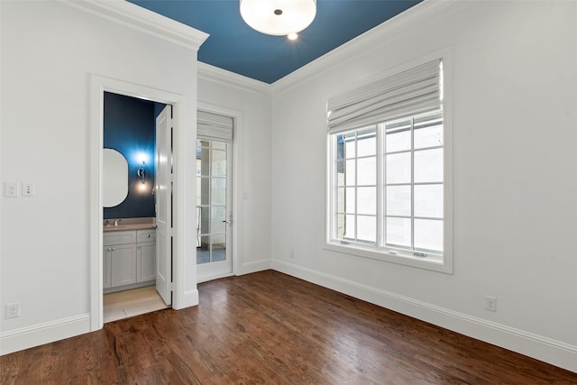 spare room with ornamental molding, wood finished floors, and baseboards