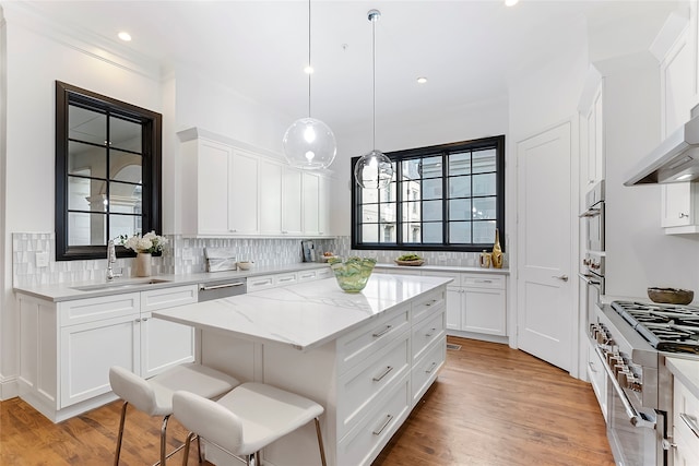 kitchen featuring sink, white cabinets, a center island, and light stone countertops