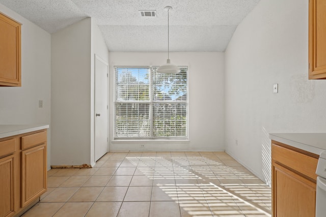 unfurnished dining area with light tile patterned flooring and a textured ceiling