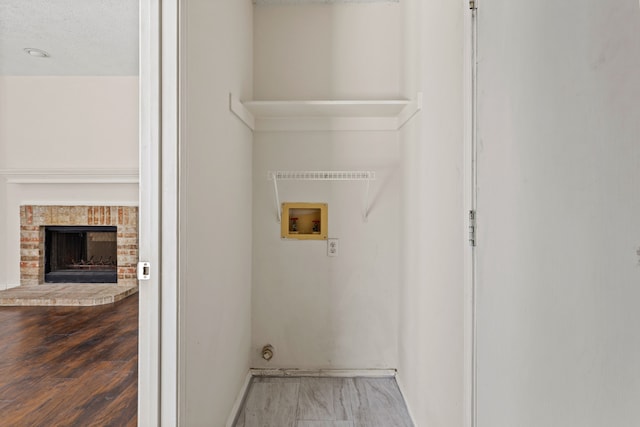 washroom with hookup for a washing machine, a fireplace, and wood-type flooring