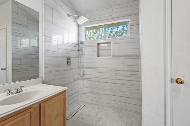 bathroom with vanity, a textured ceiling, and tiled shower