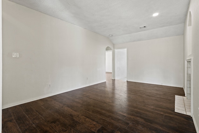 unfurnished living room with a textured ceiling, dark hardwood / wood-style floors, and vaulted ceiling