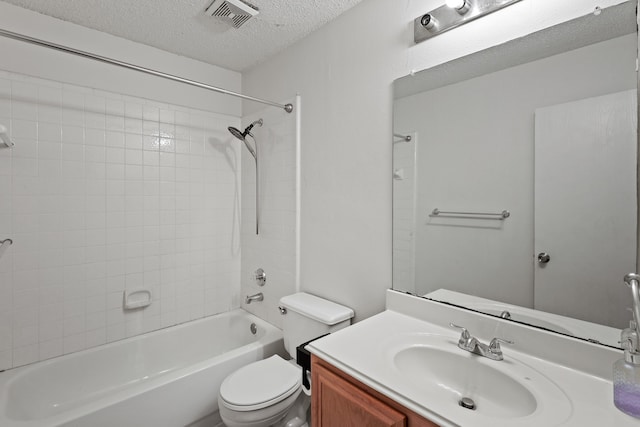 full bathroom featuring vanity, toilet, a textured ceiling, and tiled shower / bath