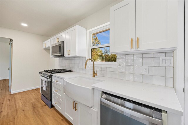 kitchen with decorative light fixtures, light wood-type flooring, white cabinetry, and appliances with stainless steel finishes