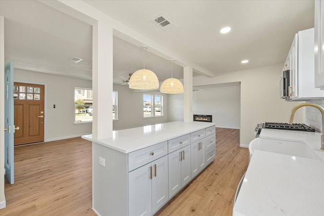 kitchen featuring white cabinets, ceiling fan, pendant lighting, and light hardwood / wood-style floors