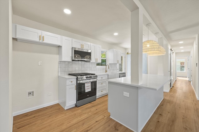 kitchen featuring white cabinets, decorative backsplash, stainless steel appliances, and light hardwood / wood-style flooring