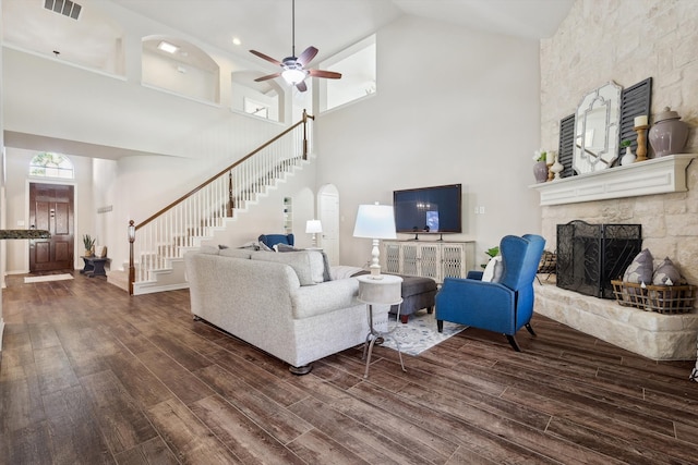 living room with dark hardwood / wood-style flooring, high vaulted ceiling, ceiling fan, and a stone fireplace