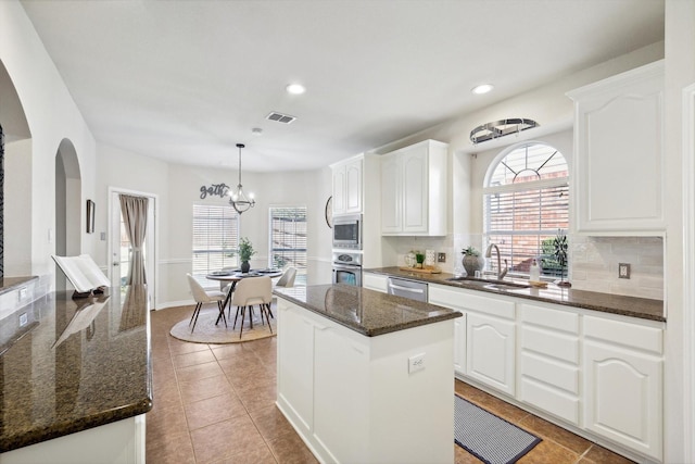 kitchen featuring stainless steel appliances, a kitchen island, sink, and white cabinets