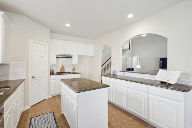 kitchen featuring white cabinets, a kitchen island, and dark stone counters