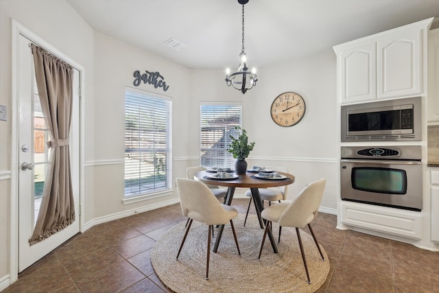 dining area with dark tile patterned flooring and an inviting chandelier