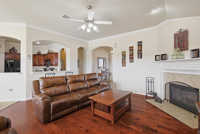 living room with ornamental molding, ceiling fan, a tile fireplace, dark hardwood / wood-style floors, and lofted ceiling