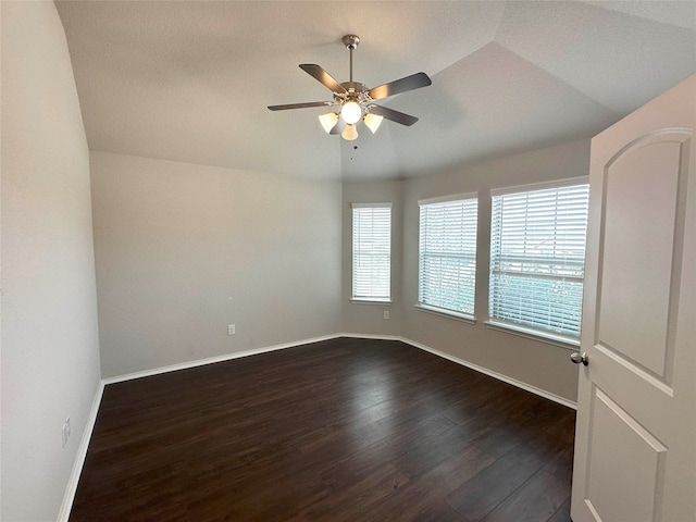 empty room featuring dark hardwood / wood-style floors, vaulted ceiling, ceiling fan, and a healthy amount of sunlight