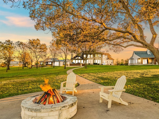 patio terrace at dusk featuring a yard and an outdoor fire pit