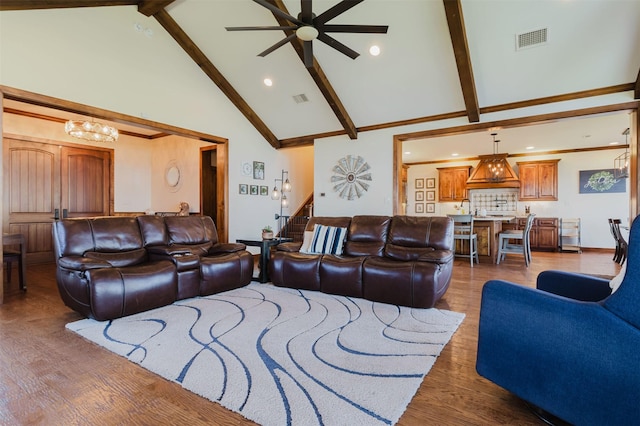 living room with ceiling fan with notable chandelier, beam ceiling, dark wood-type flooring, and visible vents