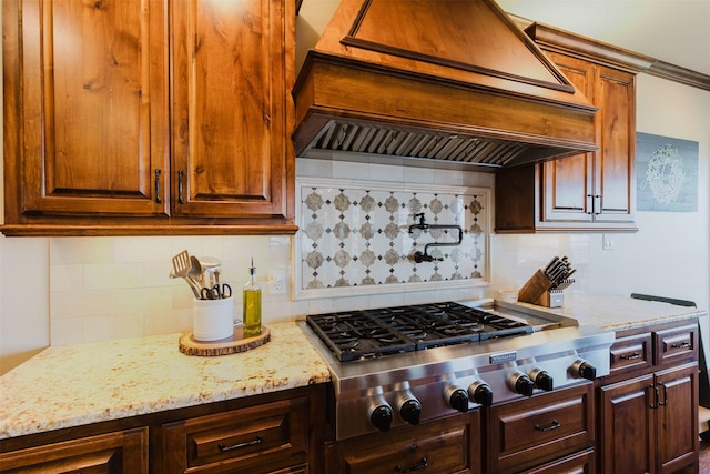 kitchen featuring backsplash, light stone countertops, custom exhaust hood, and stainless steel gas stovetop